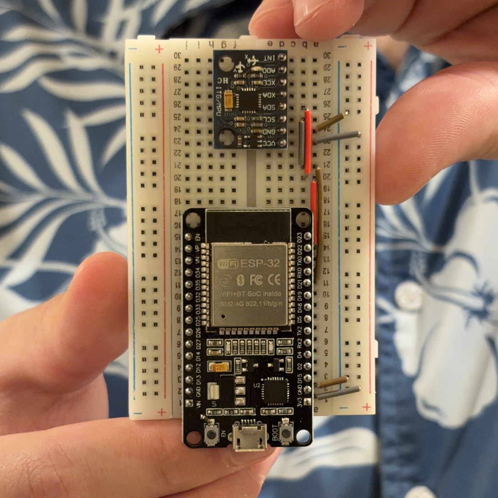 The first prototype: an ESP32 dev board and a gyroscope module on a breadboard, held in one hand and tethered by a USB cable.
